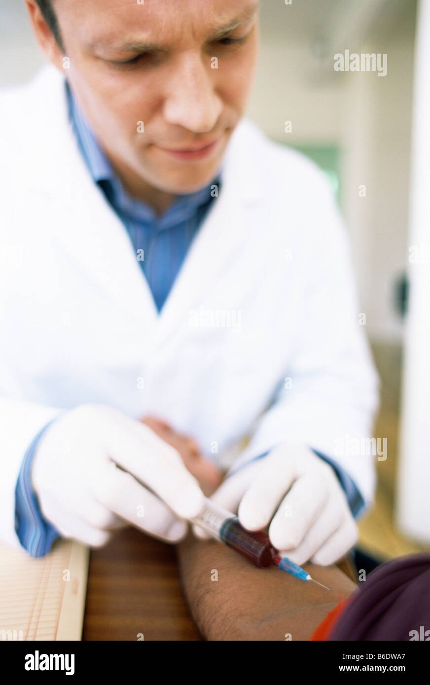 Prelievo di sangue. Medico di prendere un campione di sangue da un paziente. Il laccio rosso intorno al braccio del paziente limita il flusso sanguigno. Foto Stock