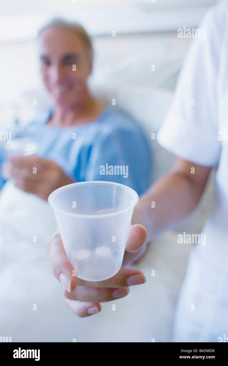 L'infermiera tenendo una tazza di pillole che lei sta per dare ad un paziente. Foto Stock