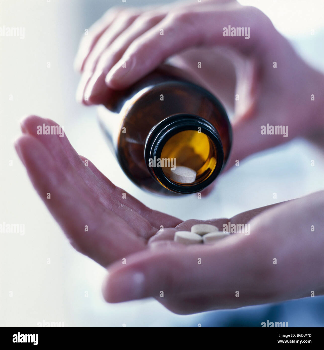 Antidolorifici. Mano versando il killer del dolore (oranalgesic) pillole da una bottiglia. Foto Stock