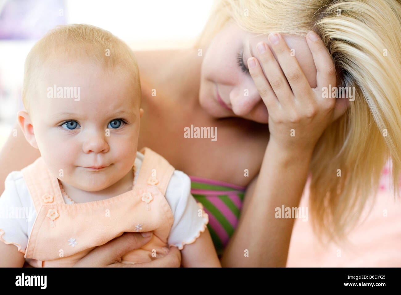 Teenage la madre e il bambino. Sottolineato giovane madre tenendo le sue 10 mesi figlia. Poste dai modelli. Foto Stock