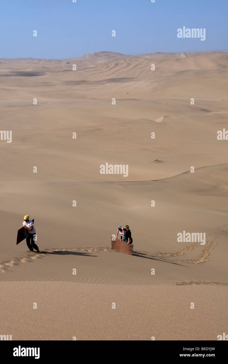 Sandboarding è molto divertente ma vi è sempre il dolore di tornare a piedi fino la duna di avere un altro andare. Swakopmund, Namibia. Foto Stock