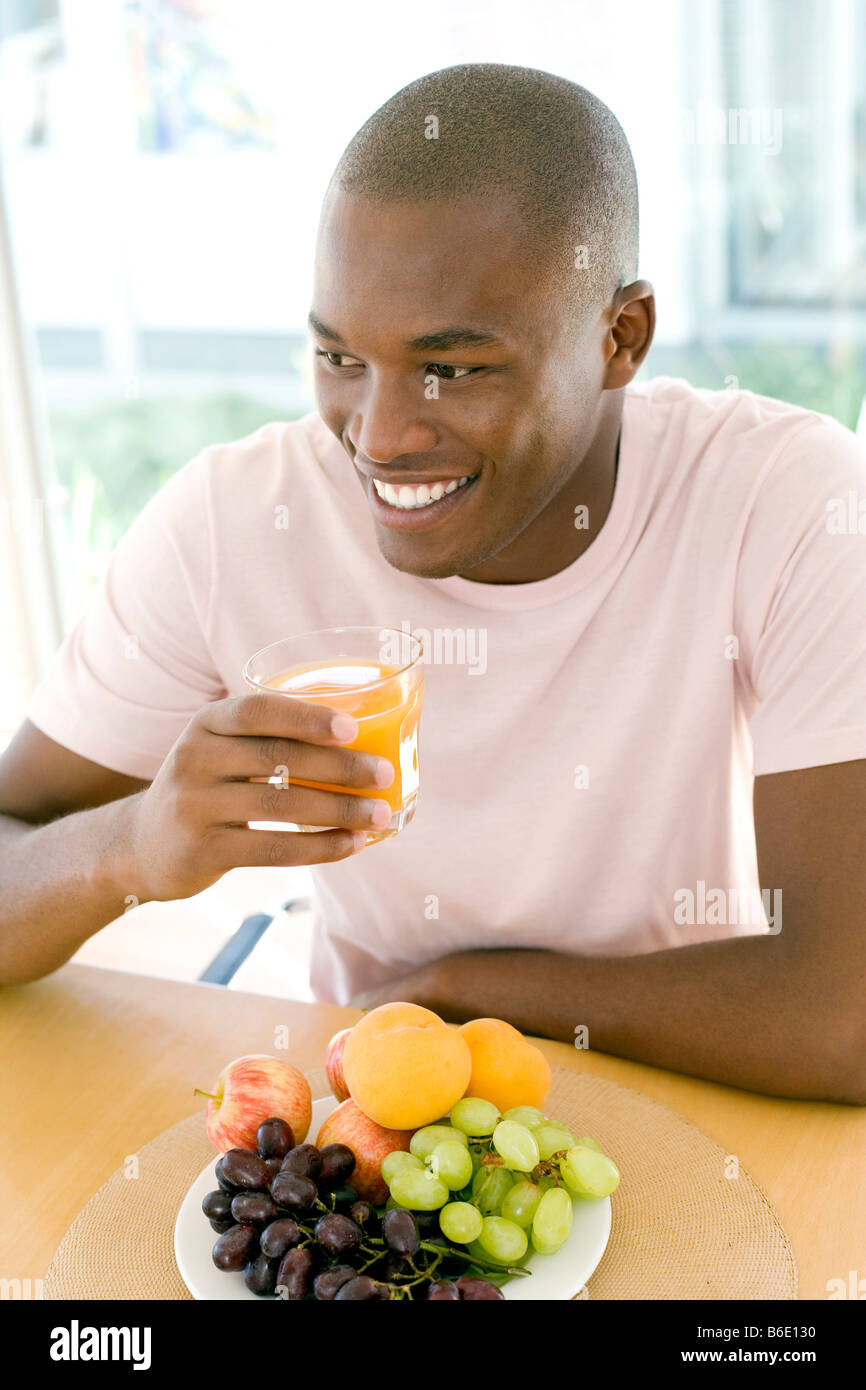 Uomo di bere succo di arancia in un tavolo da pranzo. Foto Stock