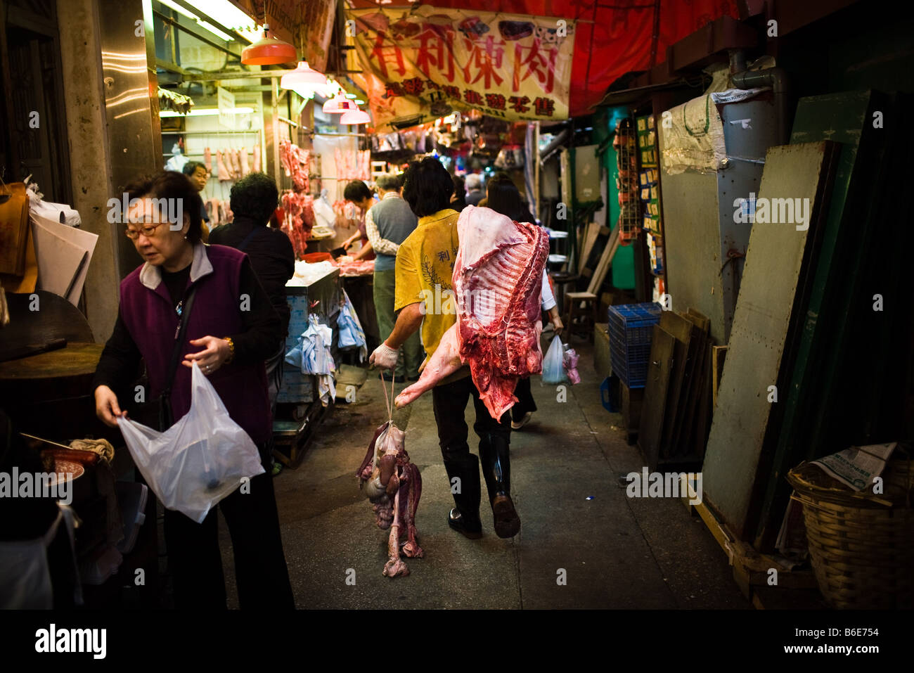 Un uomo porta carcasse di suino al mercato della carne in Hong Kong Cina Foto Stock