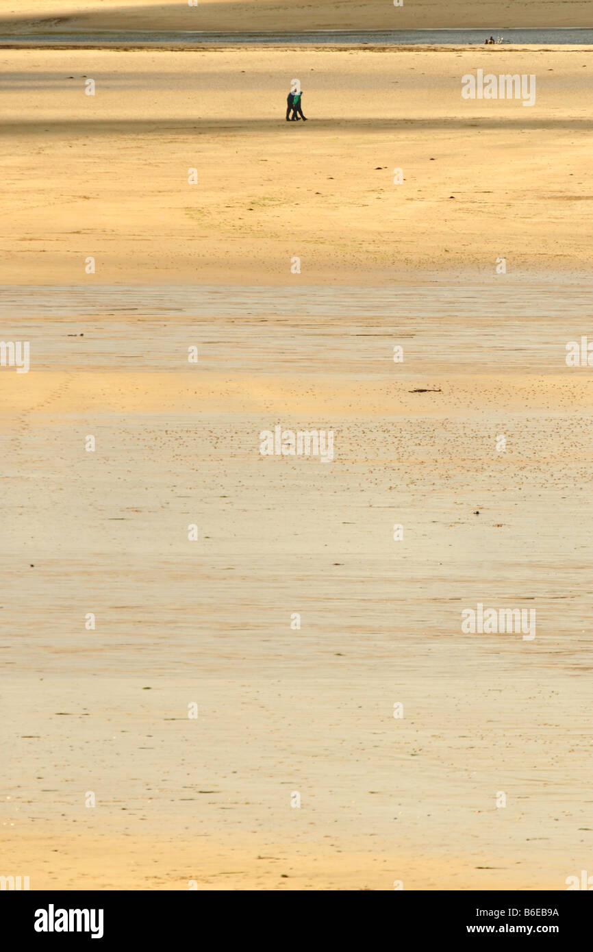 Matura in distanza camminare sulla sabbia in spiaggia Daymer in Cornwall, Regno Unito Foto Stock