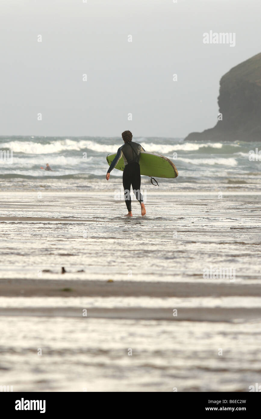 Lone Surfer teste per la mattina le onde a Polzeath Beach in Cornwall, Regno Unito Foto Stock
