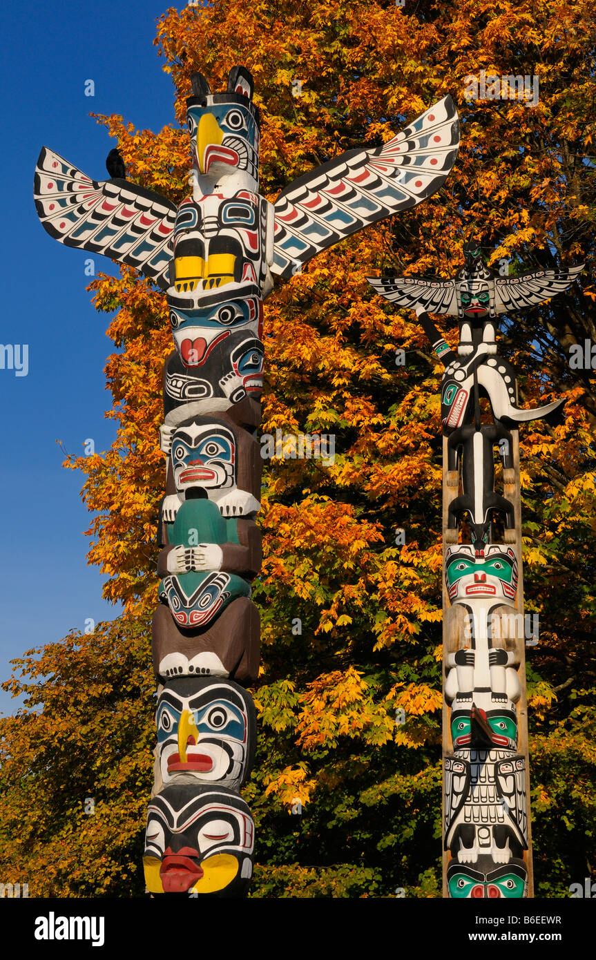 Kakasolas e Chief Wakas totem aborigena di intaglio del legno in Stanley Park a Vancouver con arancia foglie di acero Foto Stock