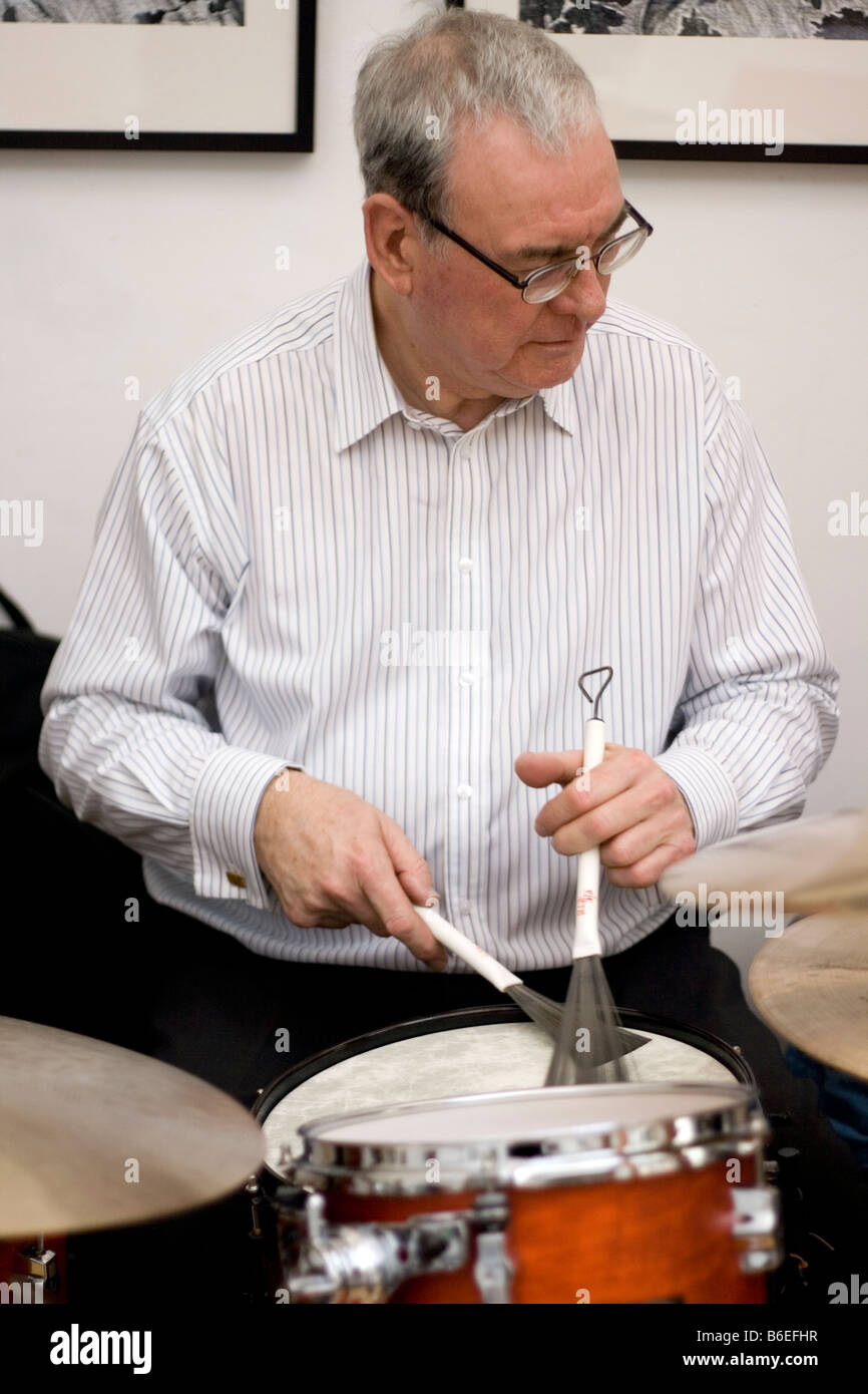 Un anziano musicista suona tamburi a un concerto durante la pausa pranzo. Foto Stock