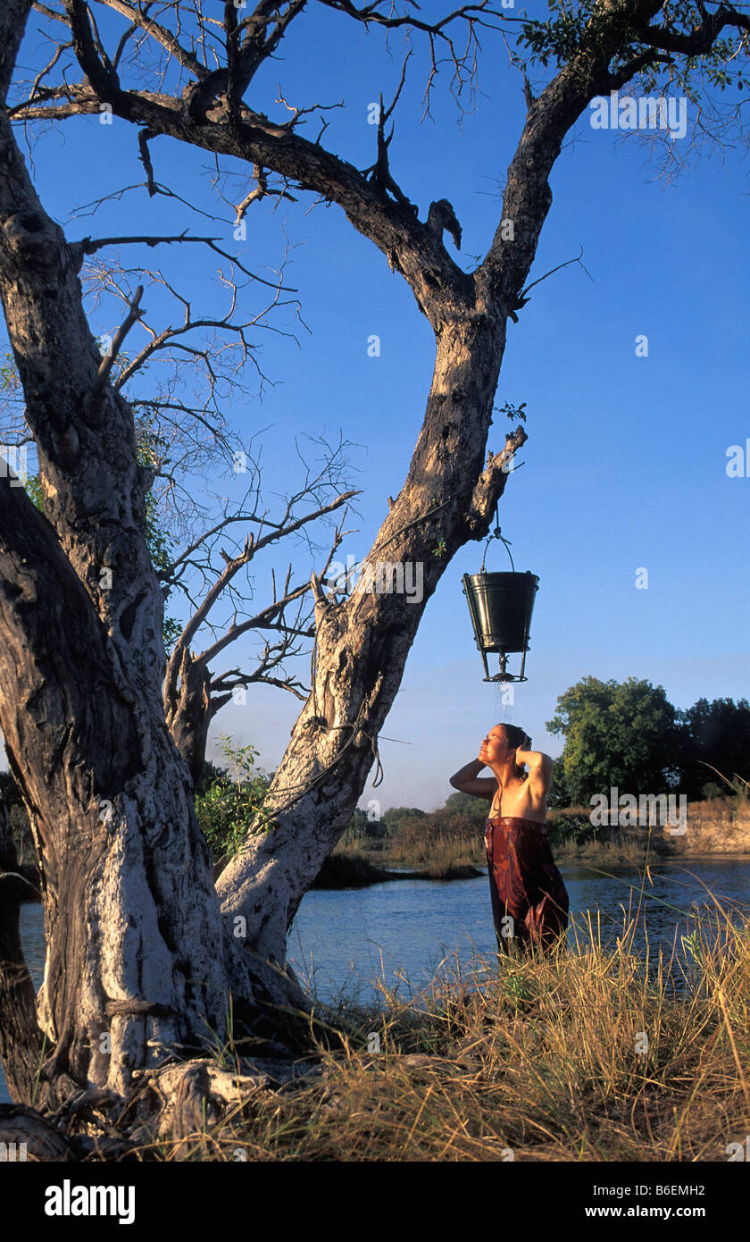 Zimbabwe Victoria Falls. Fiume Zambesi. Donna con doccia attraverso la benna appesa nella struttura ad albero. Foto Stock