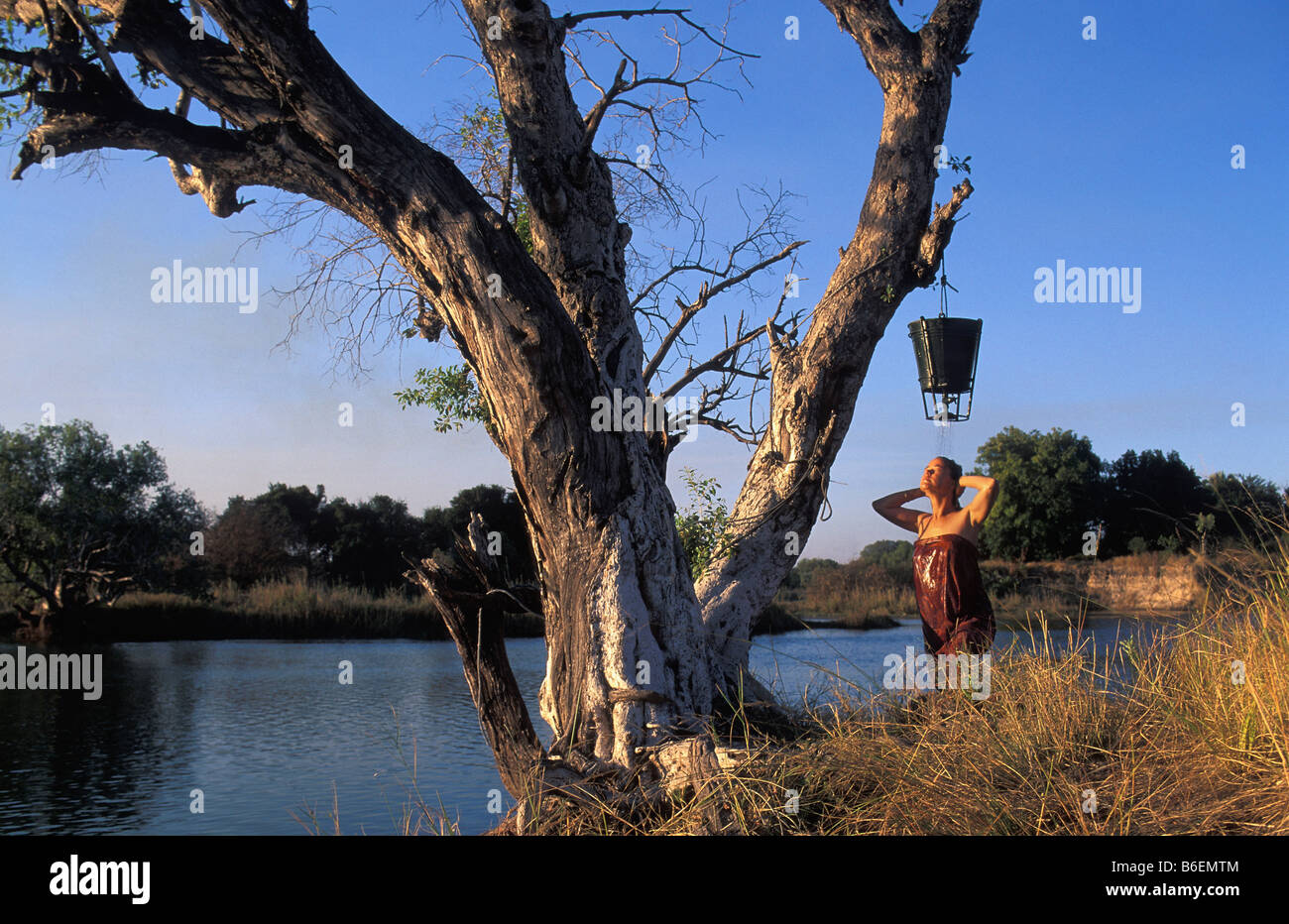Zimbabwe Victoria Falls. Fiume Zambesi. Donna con doccia attraverso la benna appesa nella struttura ad albero. Foto Stock