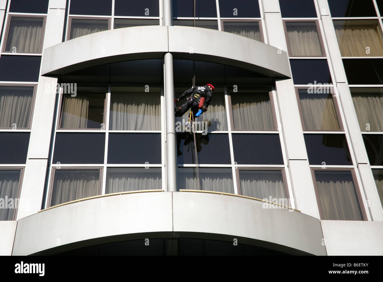 Lavoratore di manutenzione abseils giù facciata di Londra hotel Foto Stock