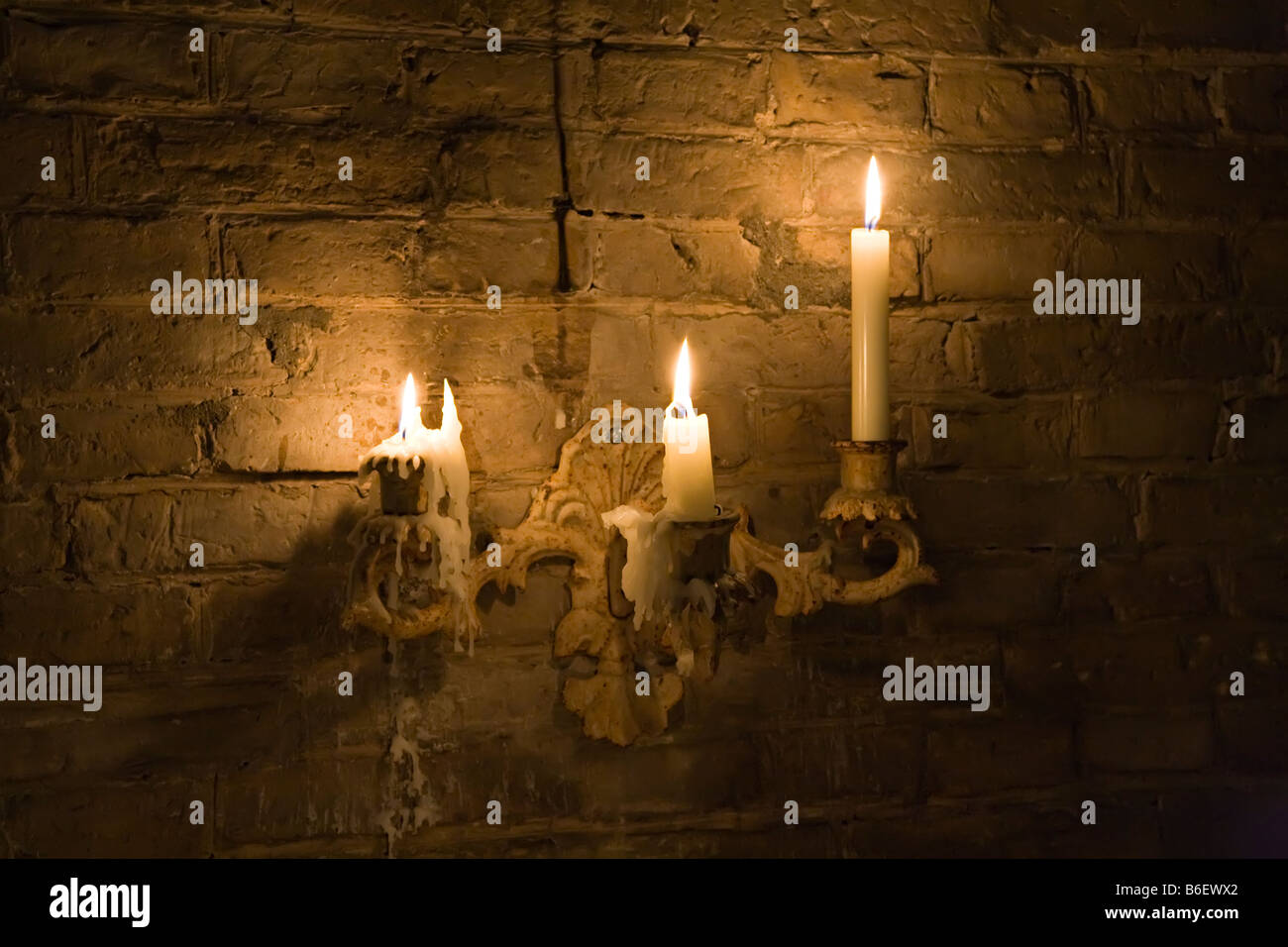 Candele accese in vecchio candelabro fissata alla parete Foto Stock