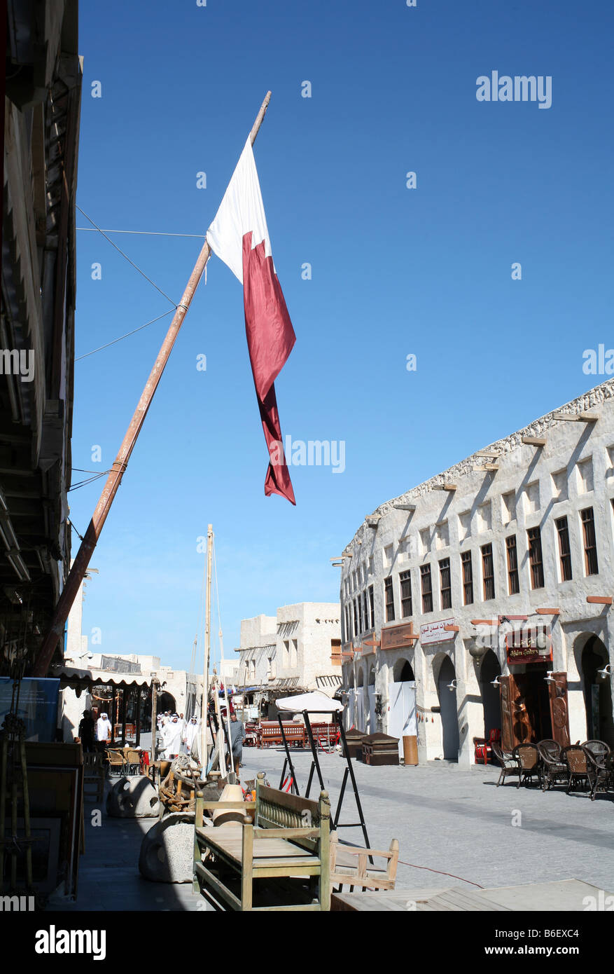 Una scena di strada nel Souq Waqif Doha in Qatar con un enorme bandiera Qatar in primo piano Foto Stock