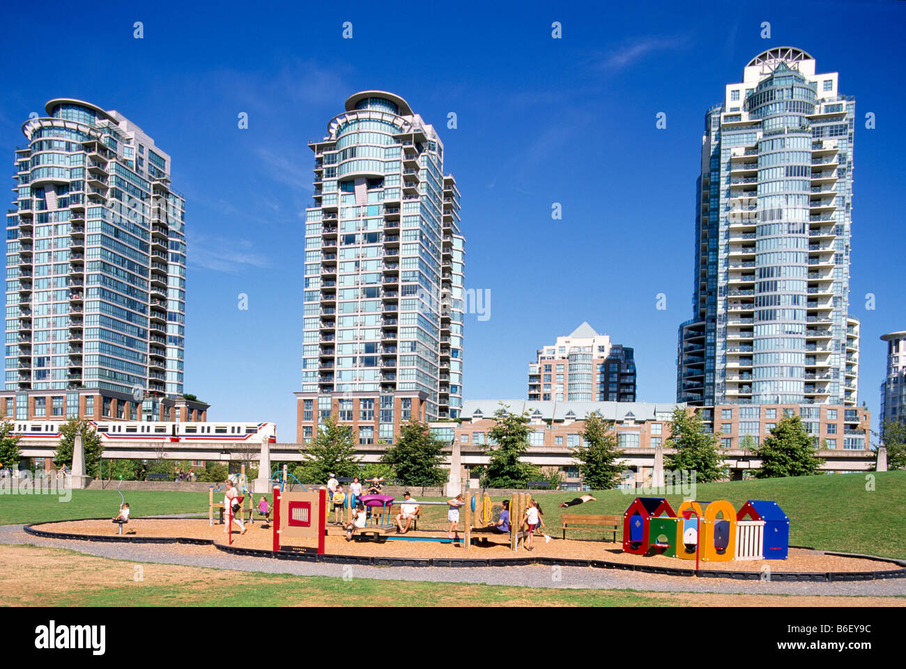 Parco giochi per bambini e alto edificio di appartamenti e di edifici condominiali nel centro cittadino di Vancouver British Columbia Canada in estate Foto Stock