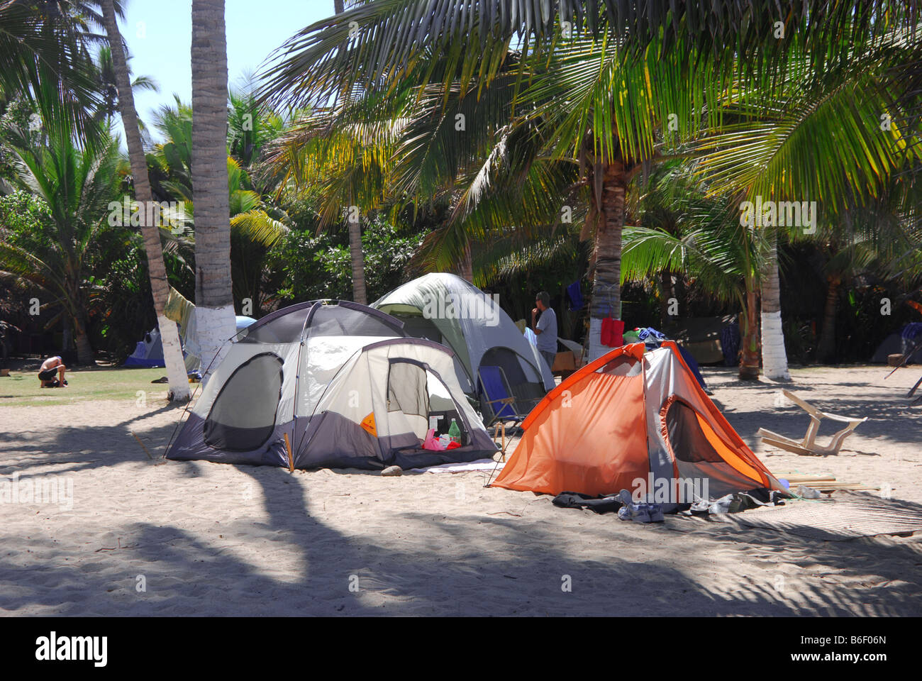 Leggero e colorato tende campeggio tra alberi di palma in Los Camarones campeggio sul bordo della spiaggia di Sayulita, Messico Foto Stock