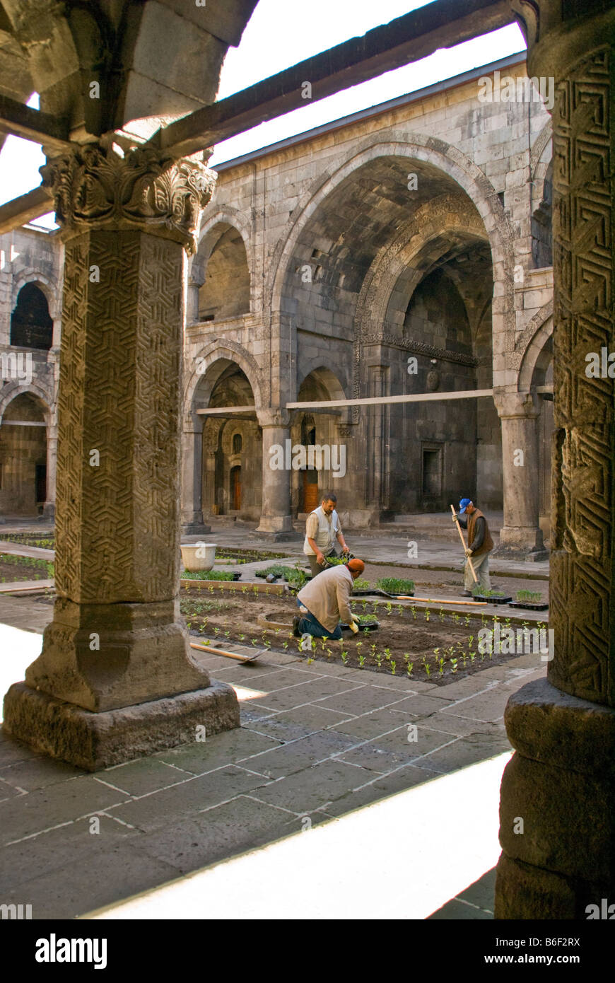 Erzurum's Cifte Medrese, cortile con operai ripristino giardino, Seljuk Turk architettura costruita nel 1236 Foto Stock