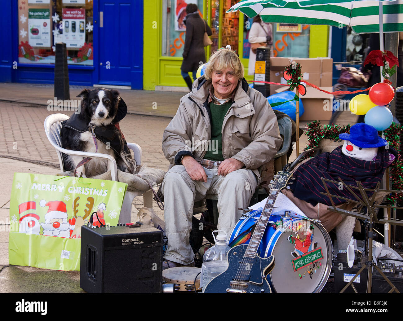 Un suonatore ambulante di strada e cane prendendo una pausa dal gioco Foto Stock