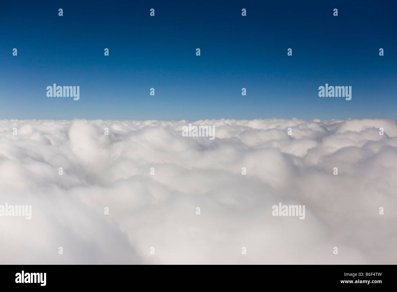 Visualizza una finestra di aereo di uno spesso strato di nuvole e il blu del cielo sopra. Foto Stock