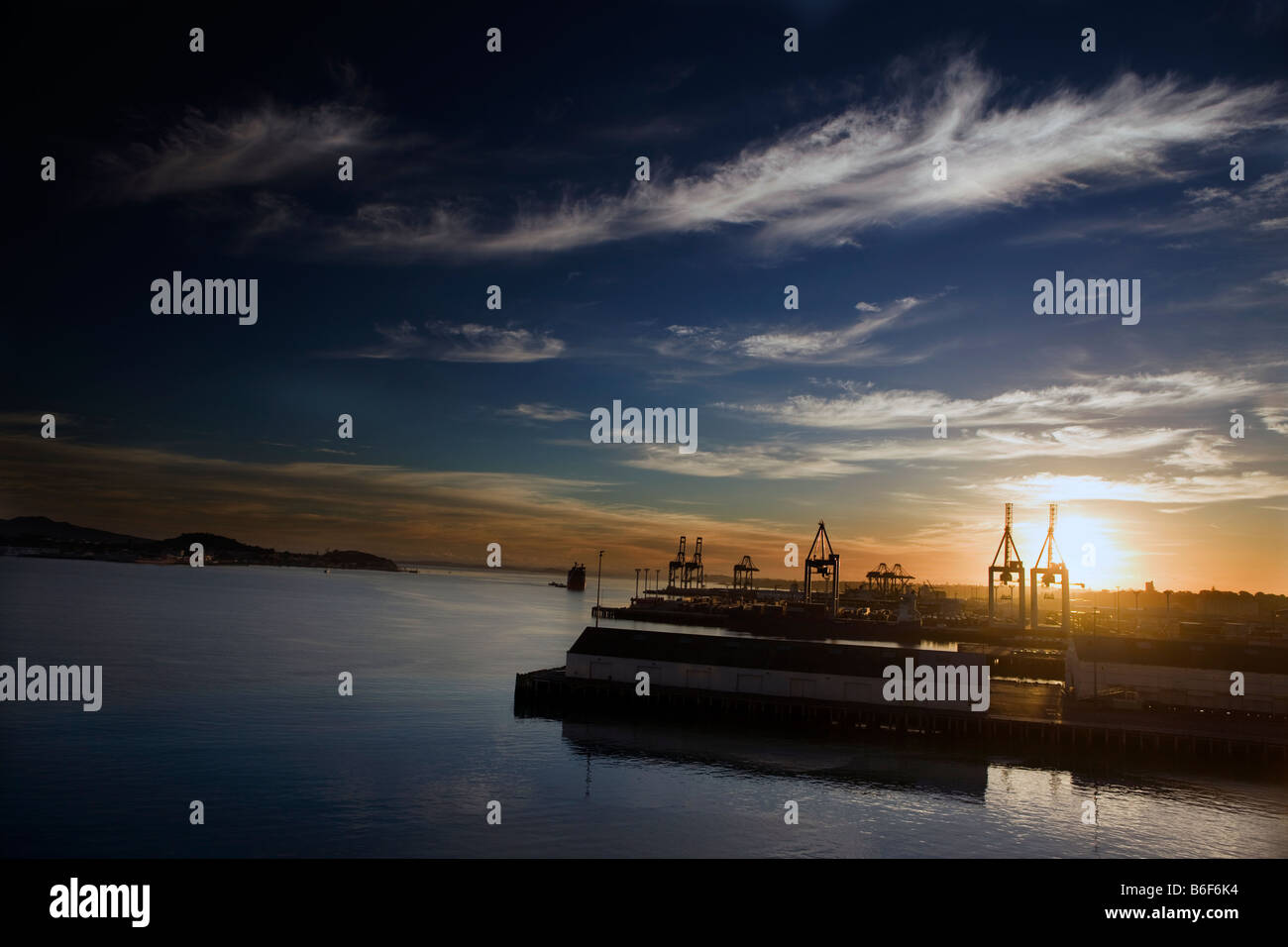 Il sole sorge oltre il porto di Waitemata di Auckland e il porto di spedizione, Auckland, Nuova Zelanda Foto Stock