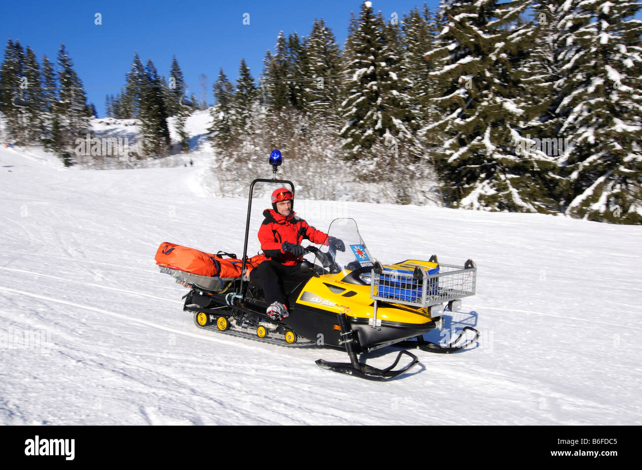 Sciatore e protezione di sci con ski-doo nella ski area di Spitzing, Alpi Bavaresi, Alta Baviera, Germania, Europa Foto Stock