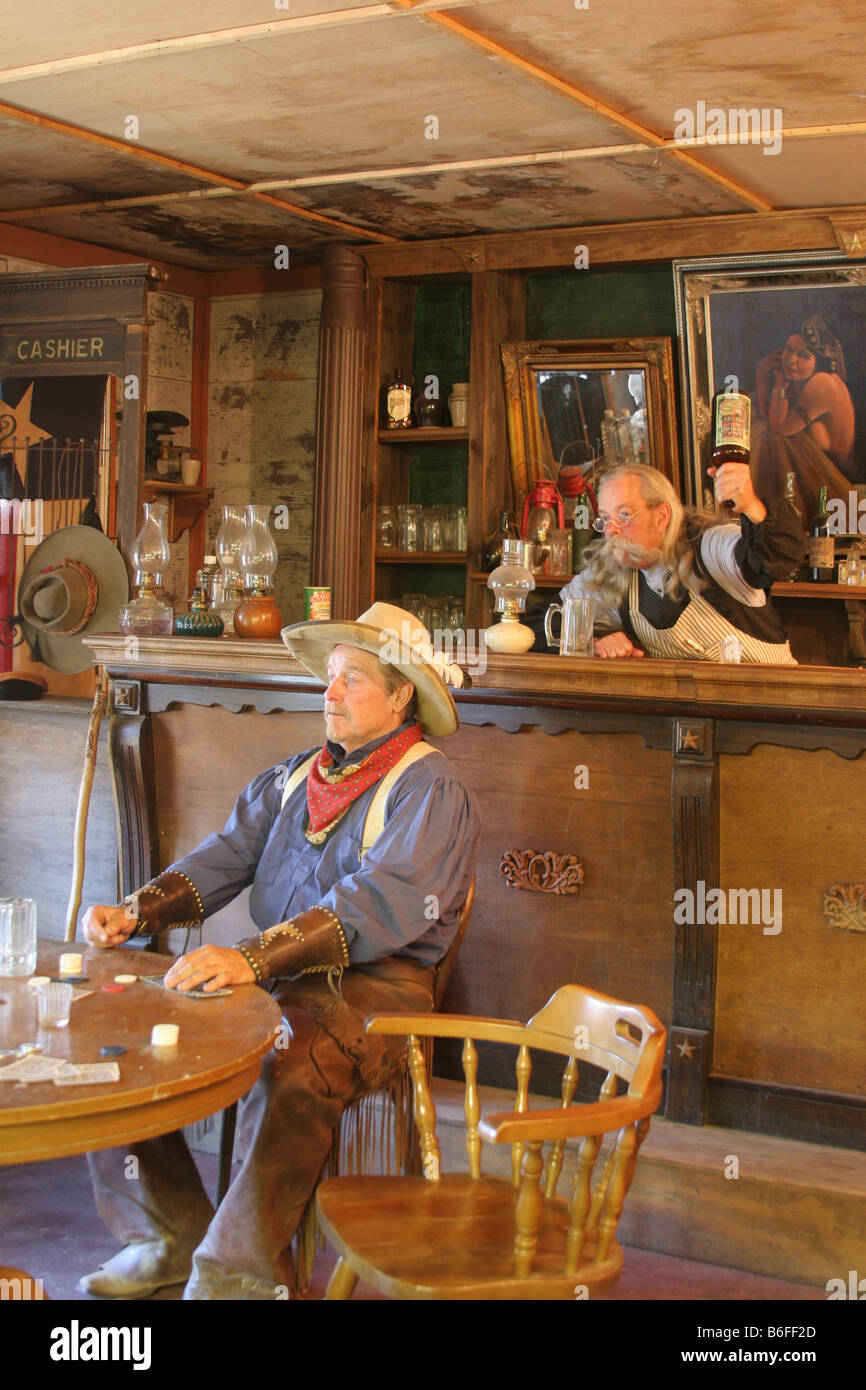 In un vecchio west saloon un cowboy è in procinto di essere colpito in testa dal barman per non pagare Foto Stock