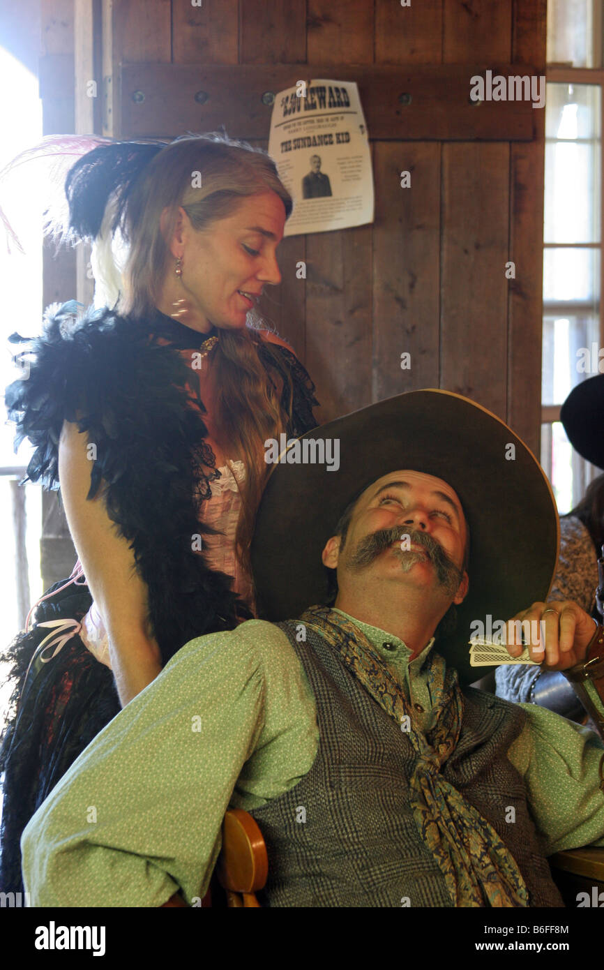 Una berlina ragazza aiutando un cowboy giocare un gioco di carte del poker Foto Stock