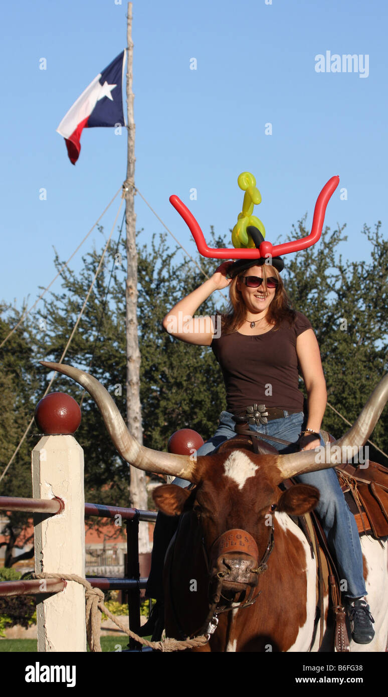 Una giovane donna di cavalcare un Texas Longhorn bestiame al Stockyards Fort Worth Texas Foto Stock