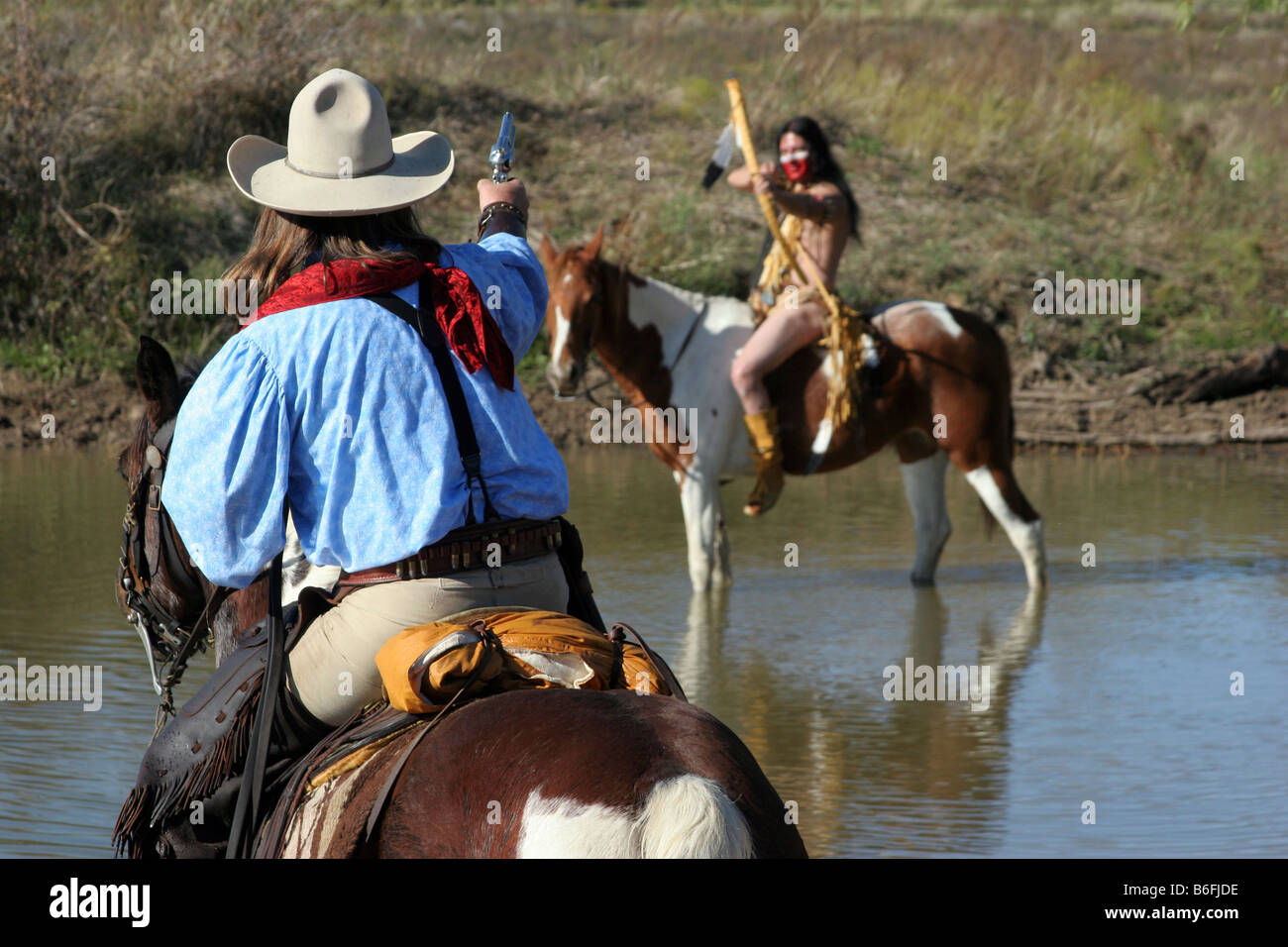 Un cowboy e dei Nativi Americani face off attraverso un corpo di acqua Foto Stock