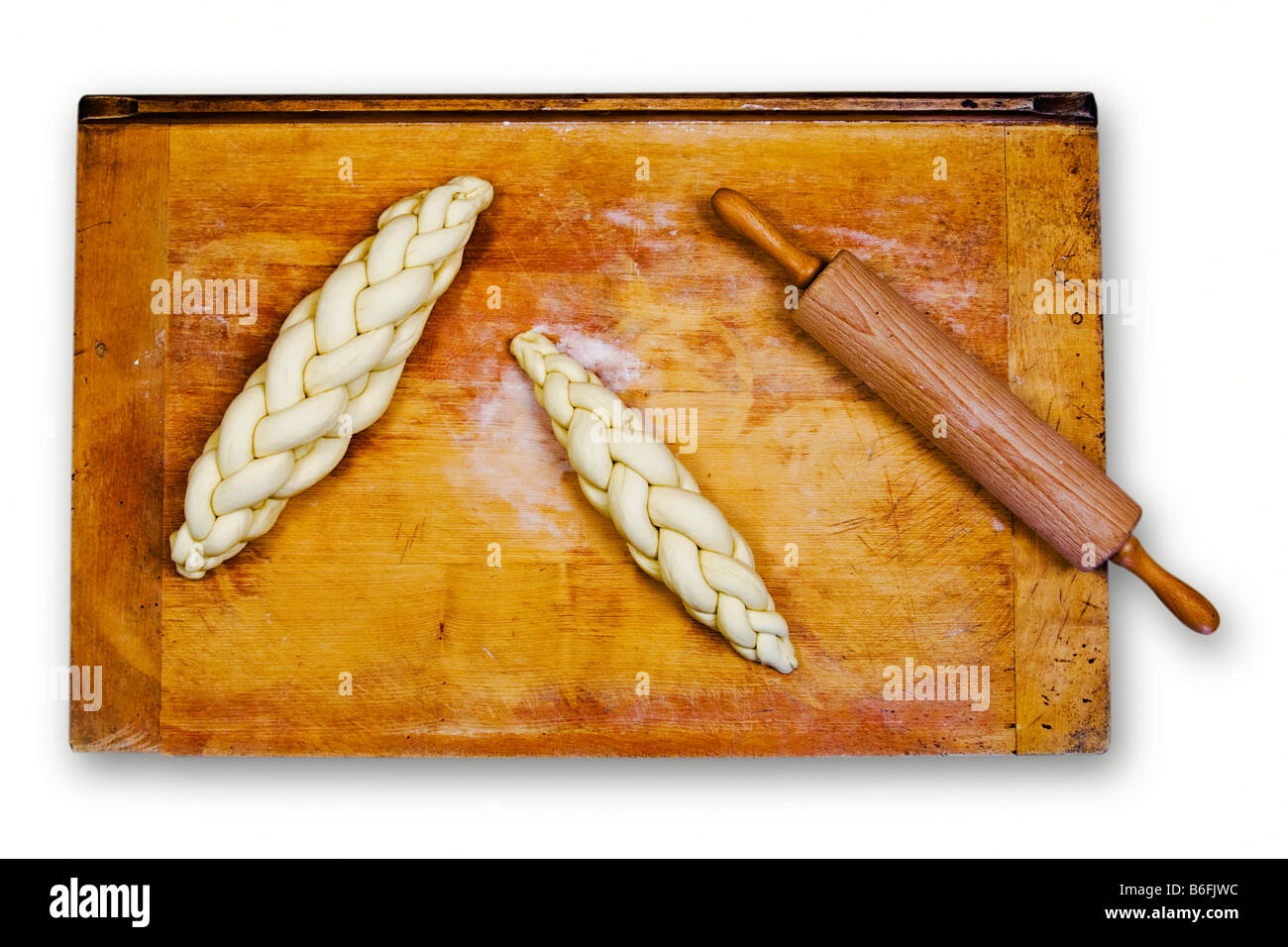 Pane a treccia o intrecciati di focaccia, crudi, su un vassoio da forno accanto a un perno di laminazione Foto Stock