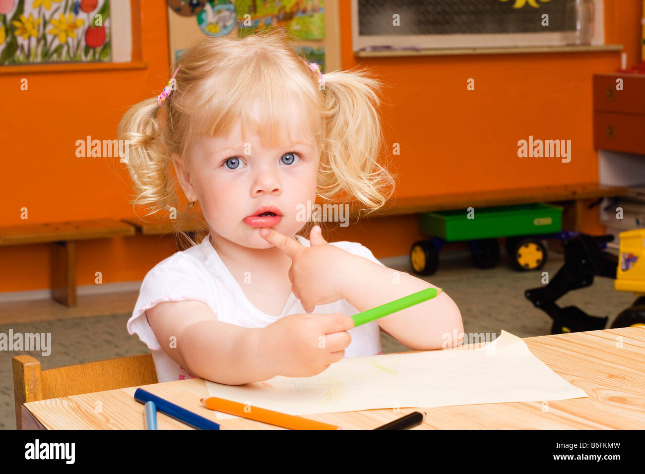 La bionda bambina di 3 anni, seduta a tavola con matite colorate Foto stock  - Alamy