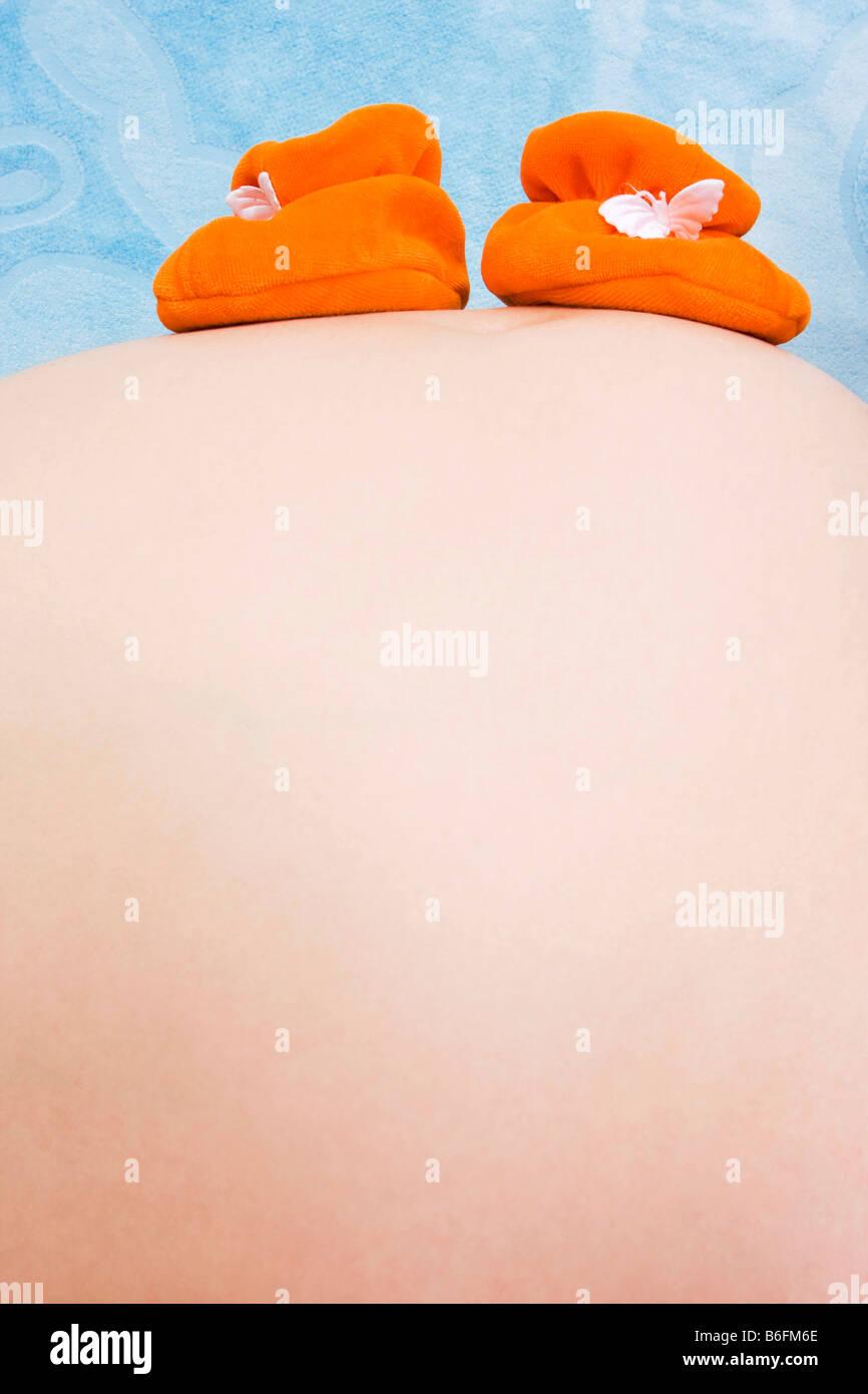 Ventre della donna incinta con bambino babbucce Foto Stock