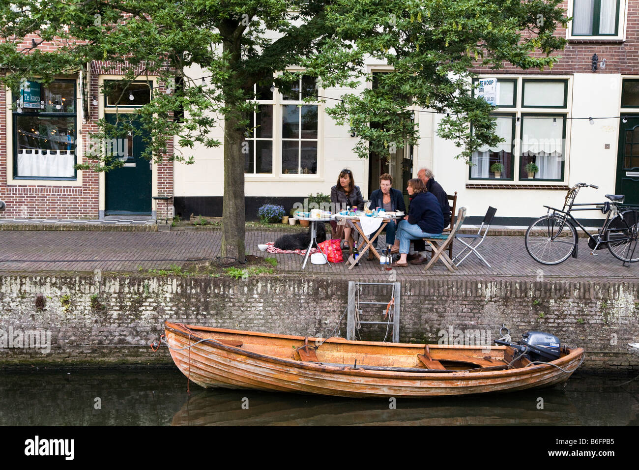 Gruppo di peolle mangiare seduti a tavola in città a bordo del canal Enkhuizen Paesi Bassi Foto Stock