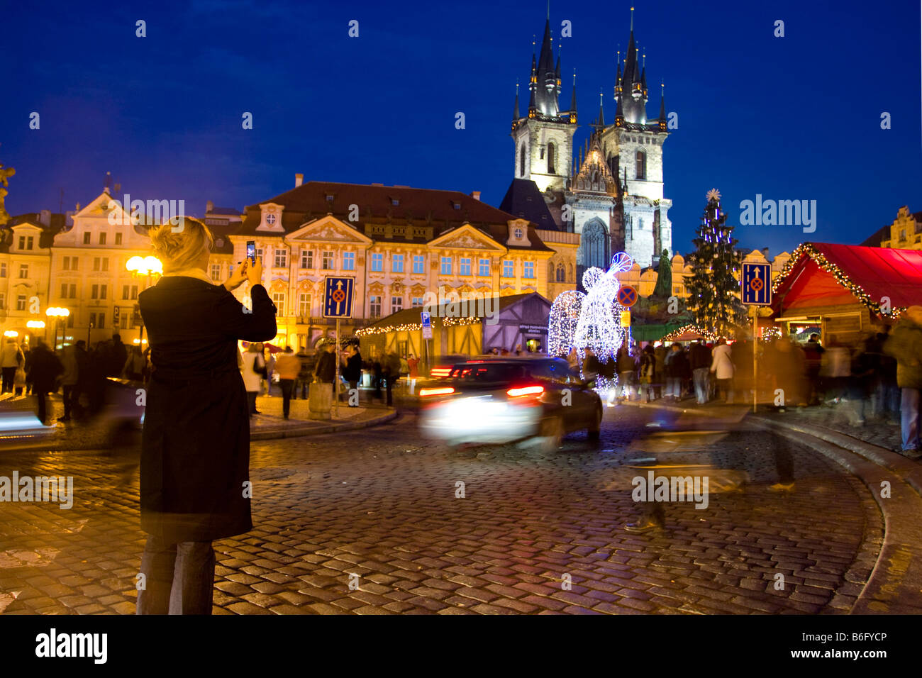 Una donna che ha scattato una foto della Piazza della Città Vecchia e della Chiesa di Tyn a Praga durante il periodo natalizio Foto Stock