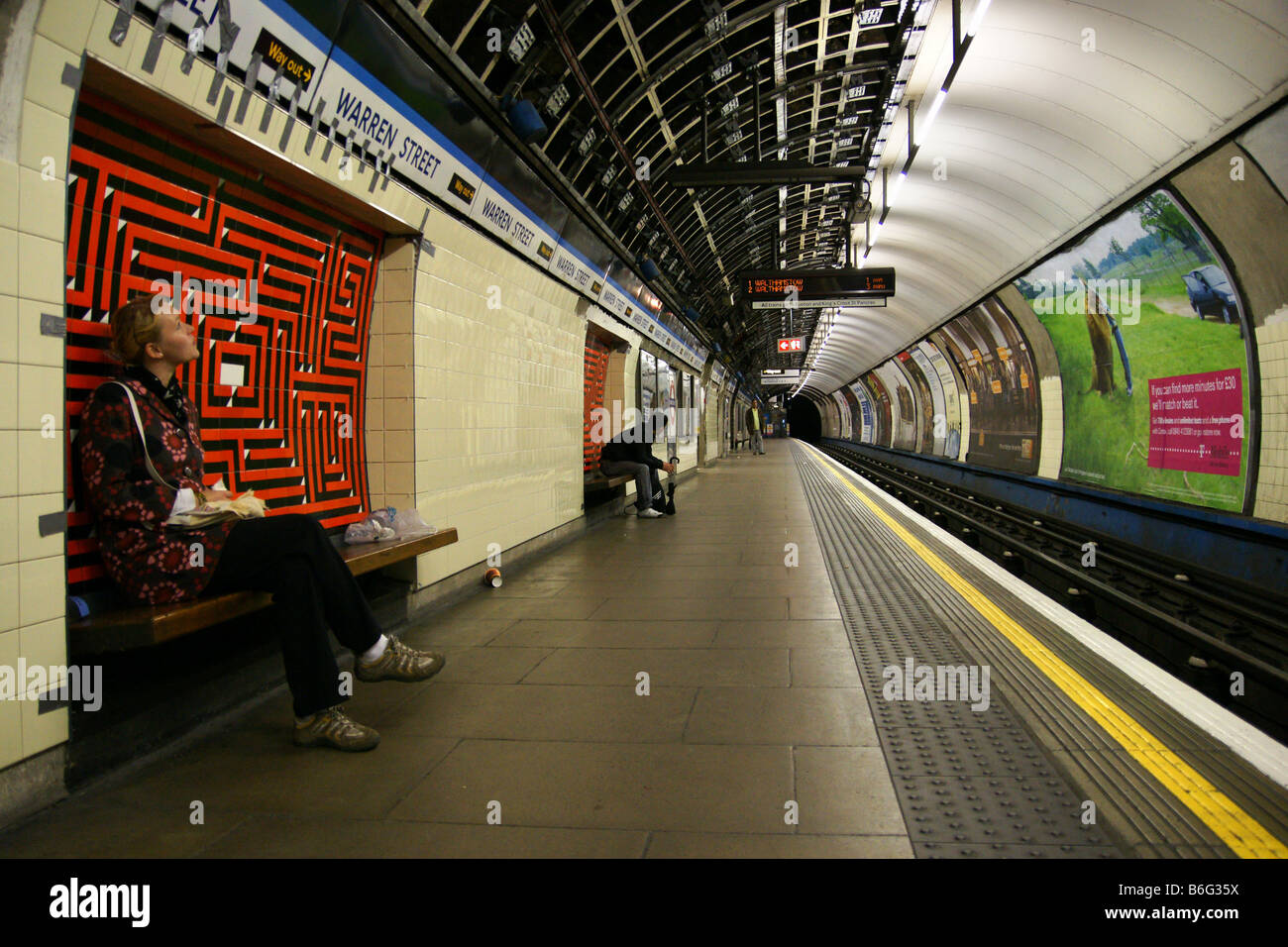 Ragazza giovane donna seduta in attesa nel tubo london underground platform Foto Stock
