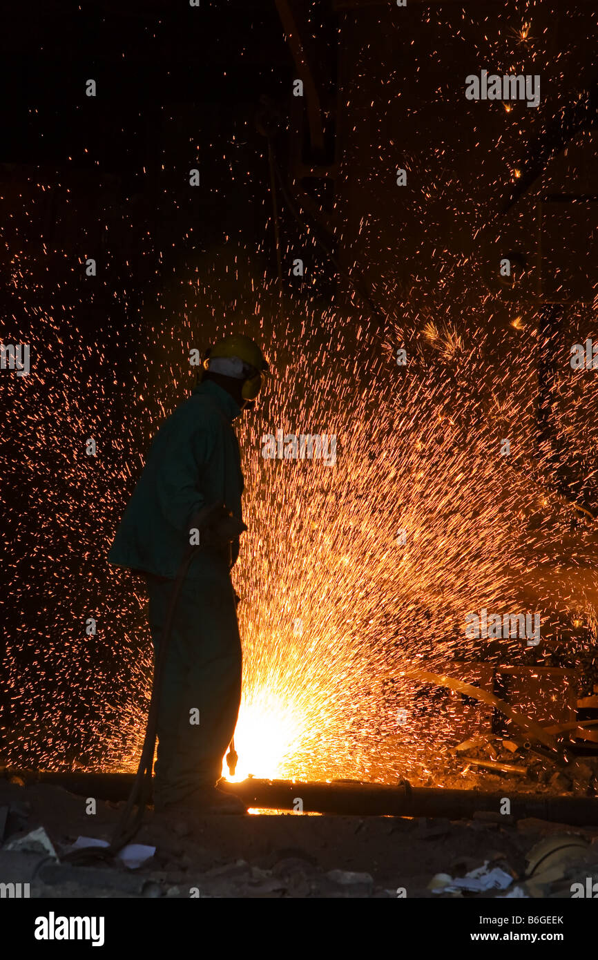 Un lavoratore utilizza una torcia e crea scintille all'interno di un mulino di acciaio. Foto Stock