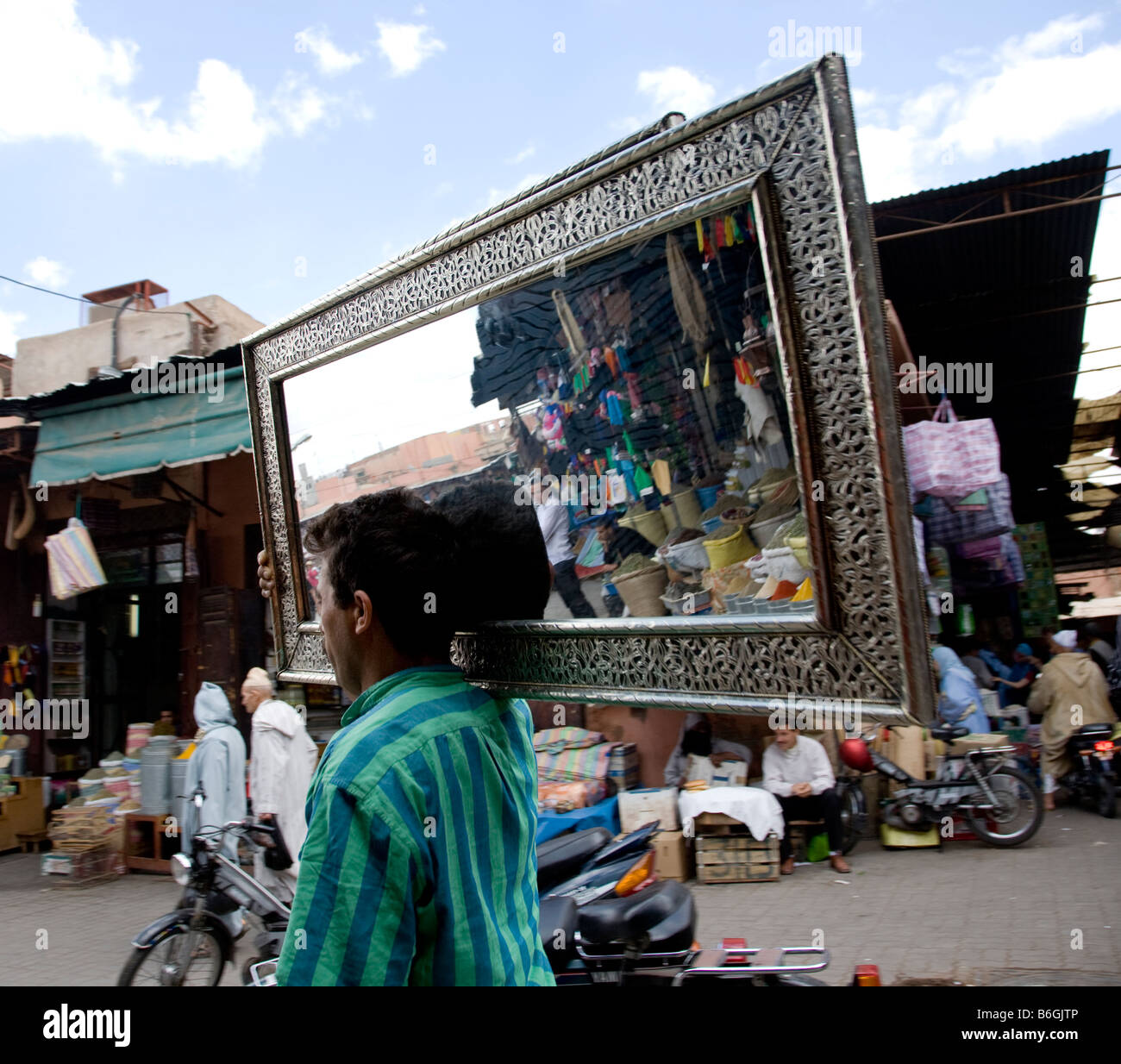 Un negoziante porta uno specchio attraverso i vicoli affollati dei souk di Marrakech Foto di Matt potrebbe Foto Stock