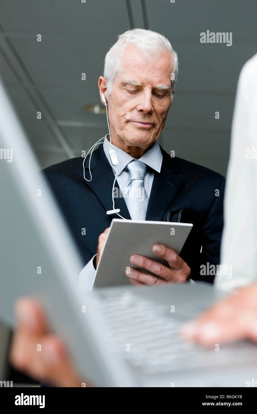 Uomo anziano con telefoni di testa prendendo appunti Foto Stock