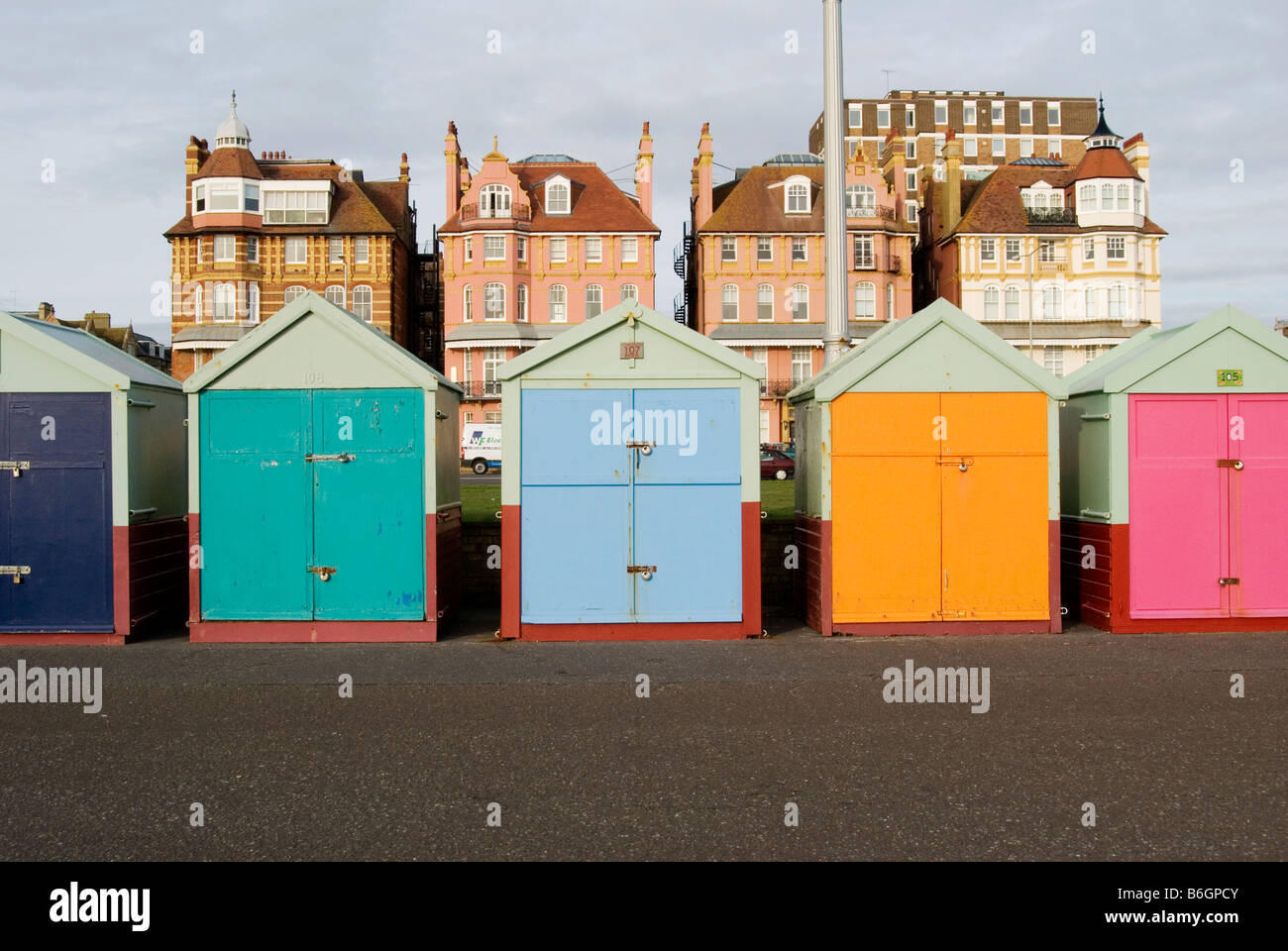 Una fila delle colorate cabine mare linea il lungomare di Brighton con città appartamenti indipendente alto dietro Foto Stock