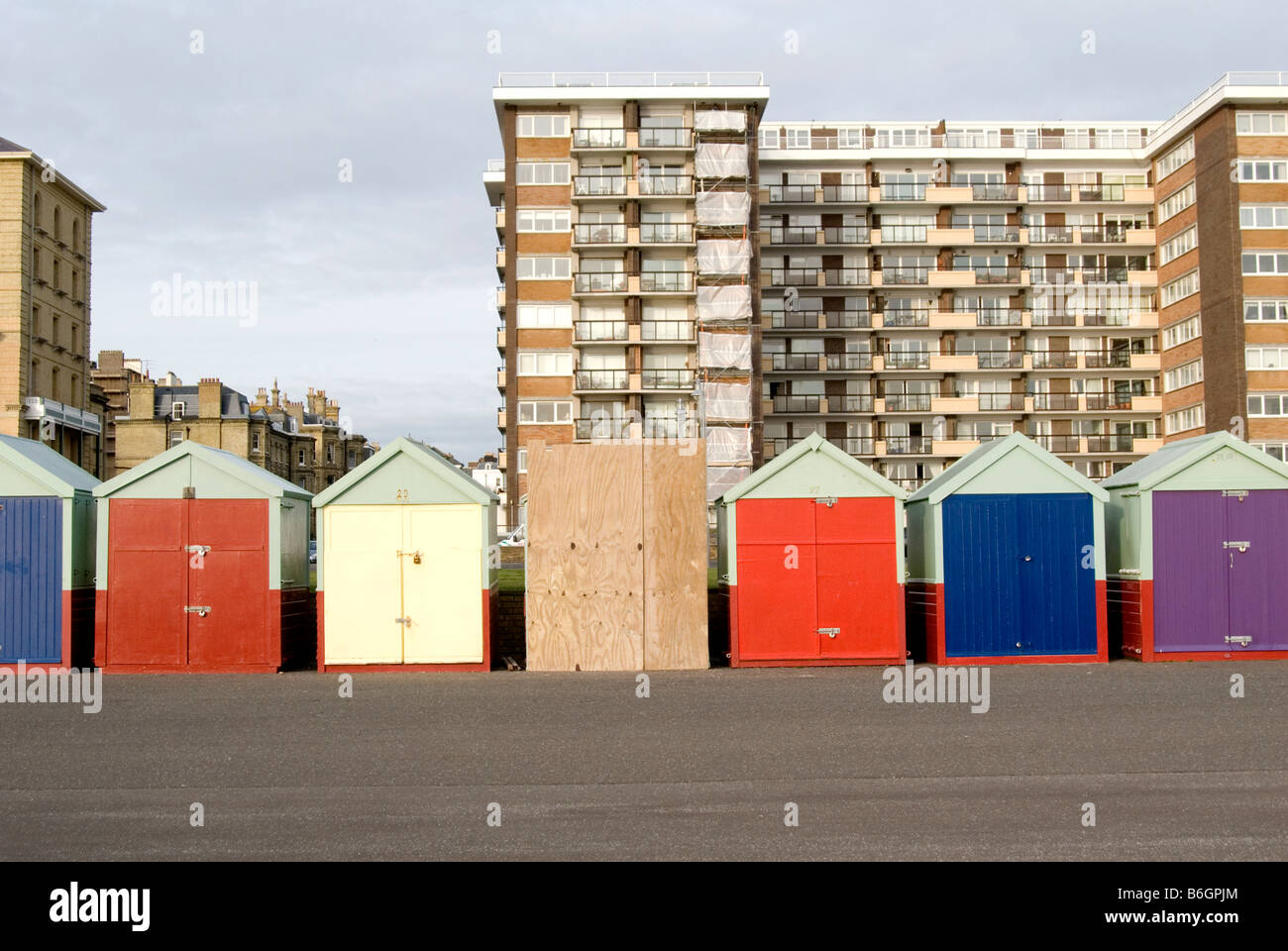 Una immagine della pittoresca spiaggia di capanne in Brighton con un blocco di appartamenti in background e scheda tra la spiaggia di capanne. Foto Stock