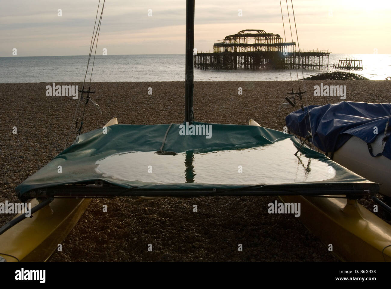 Un immagine guardando attraverso un catamarano al tramonto a Brighton con il Molo di Ponente visto dietro. L'acqua ha raccolto sul catamarano Foto Stock