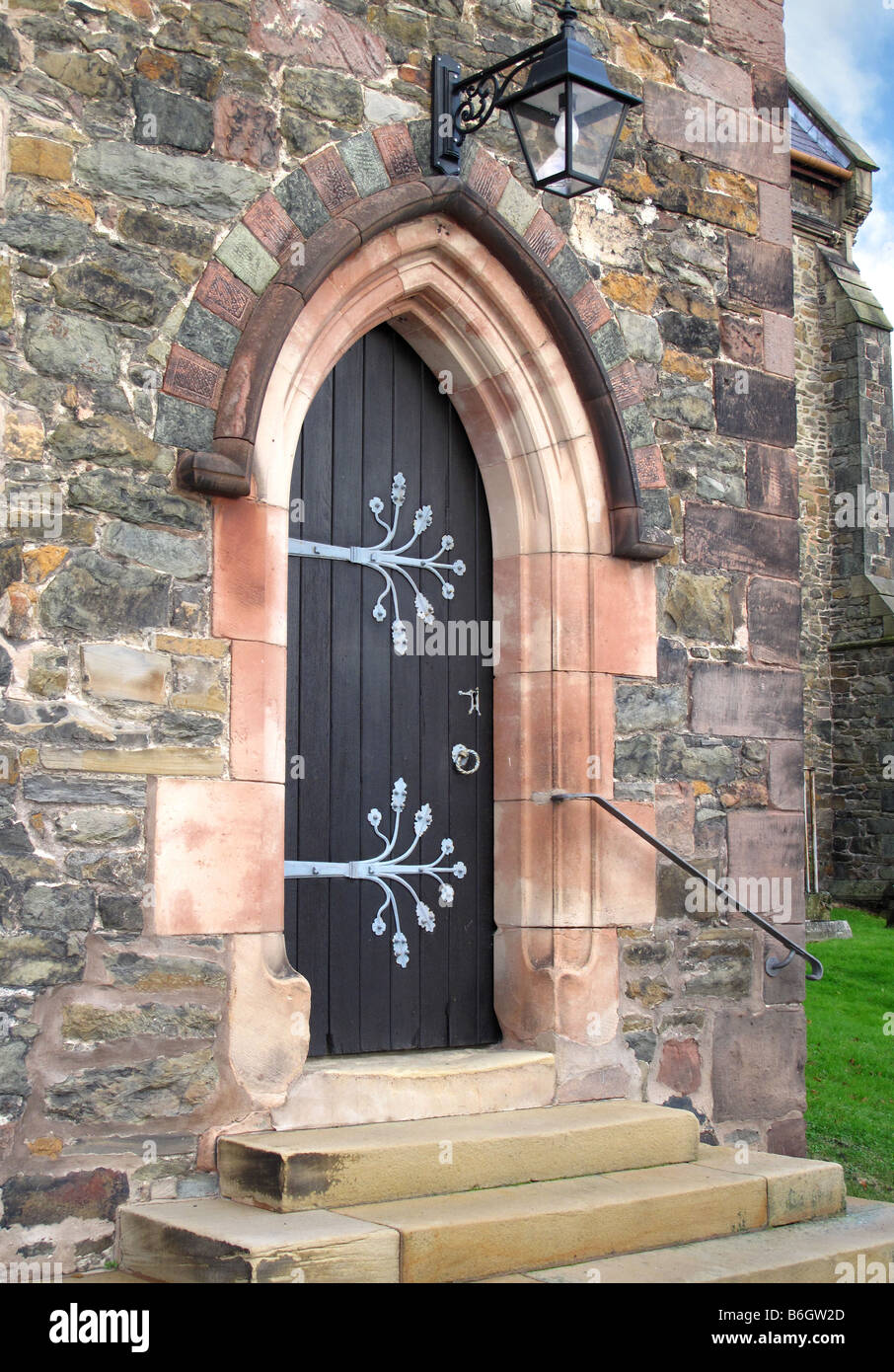 Chiesa di pietra portale ad arco e porta in legno ornato di lamiera cerniere, gradini in pietra e ghisa lanterna sopra. Foto Stock