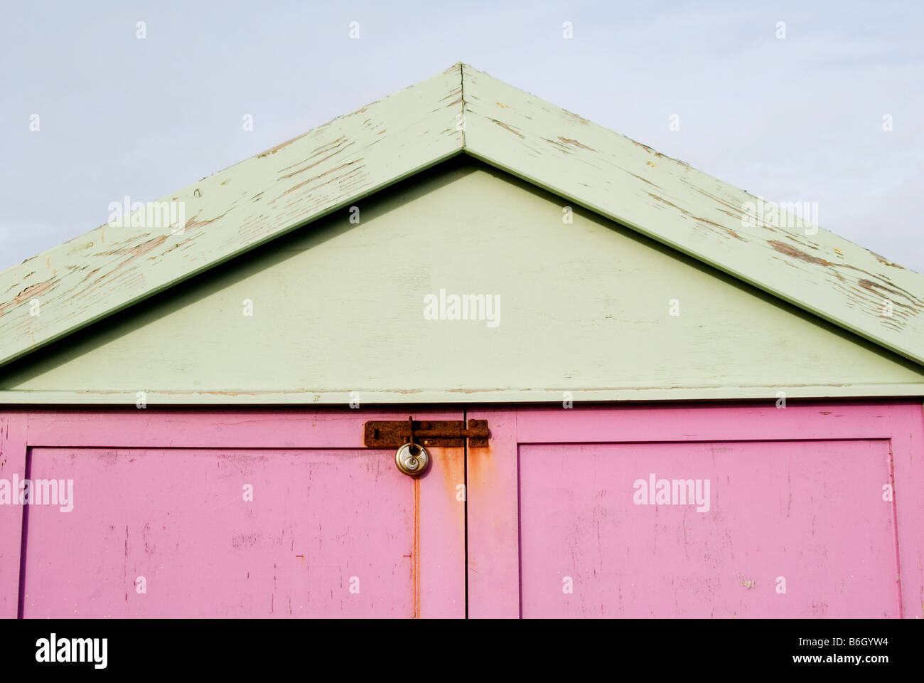 Una immagine della parte superiore della capanna sulla spiaggia con le porte dipinte di rosa e il tetto verniciato di verde, la serratura della porta è arrugginito Foto Stock
