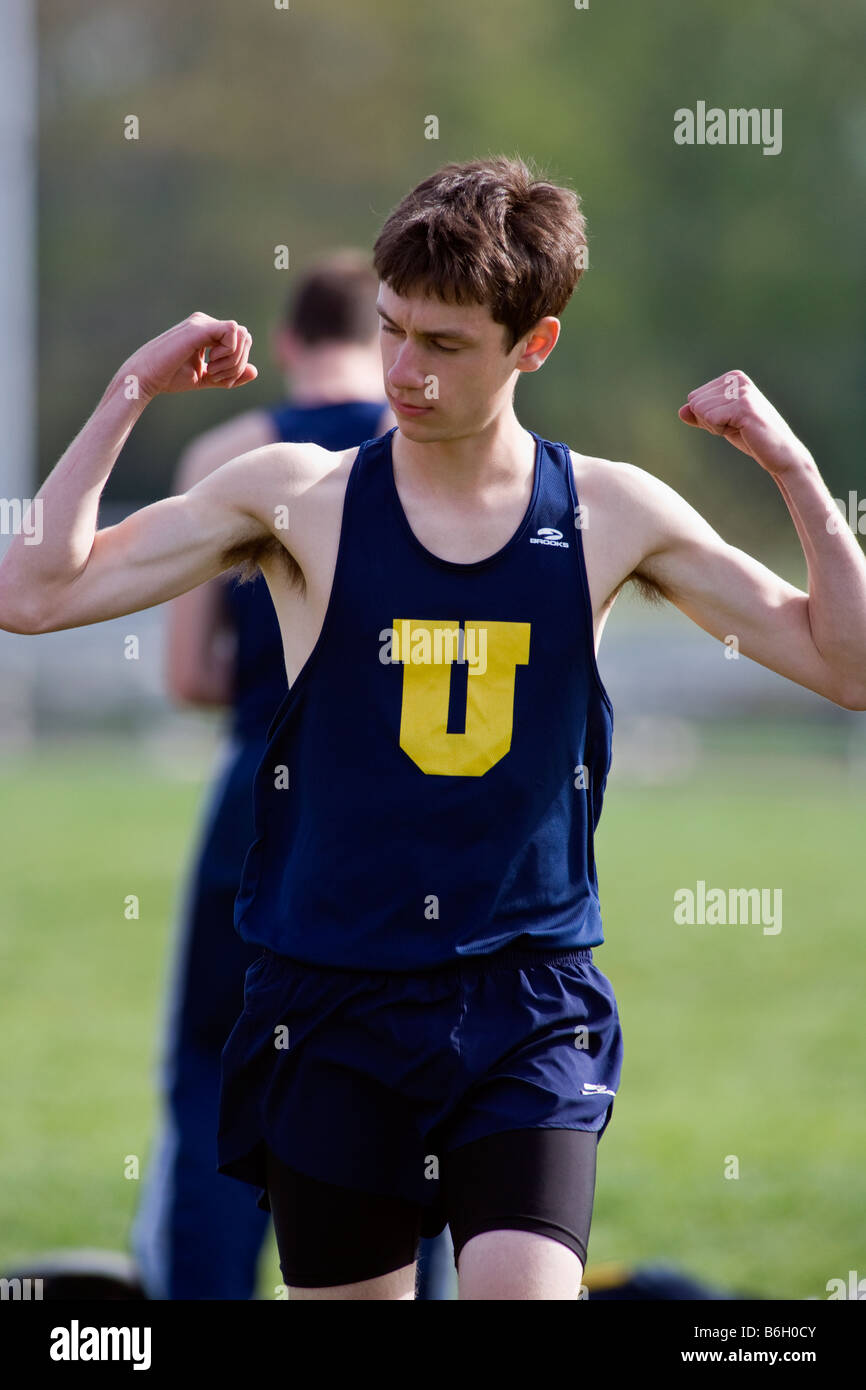 Ragazzo adolescente flettendo i suoi muscoli ad una high school Track & Field soddisfare Foto Stock