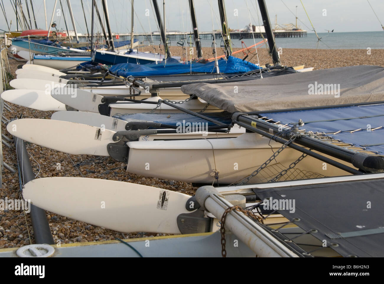 Un colpo alla ricerca di una linea di imbarcazioni timoni tutti bloccata sulla spiaggia di Brighton. Palace Pier può essere visto in background Foto Stock