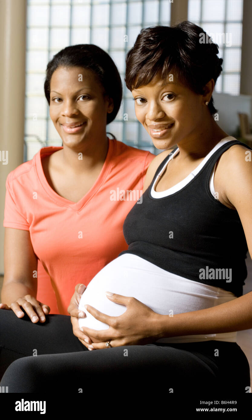 Donna incinta facendo esercizi con personal trainer. La donna è di 6 mesi di gravidanza. Foto Stock
