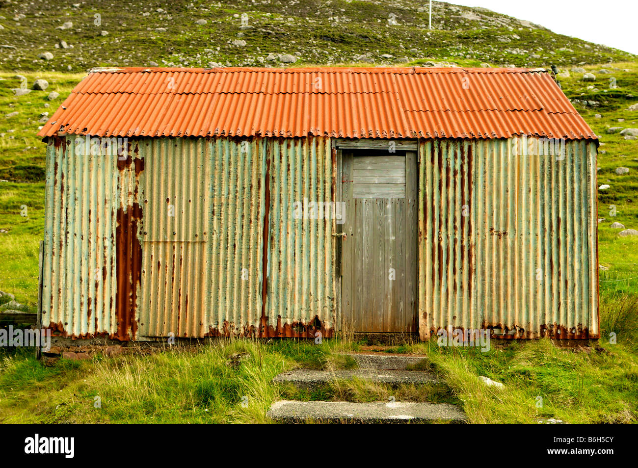 Stagno Wriggly shack, ferro corrugato edificio in Tarbeart Lewis Scozia che mostra l'età e colore Foto Stock