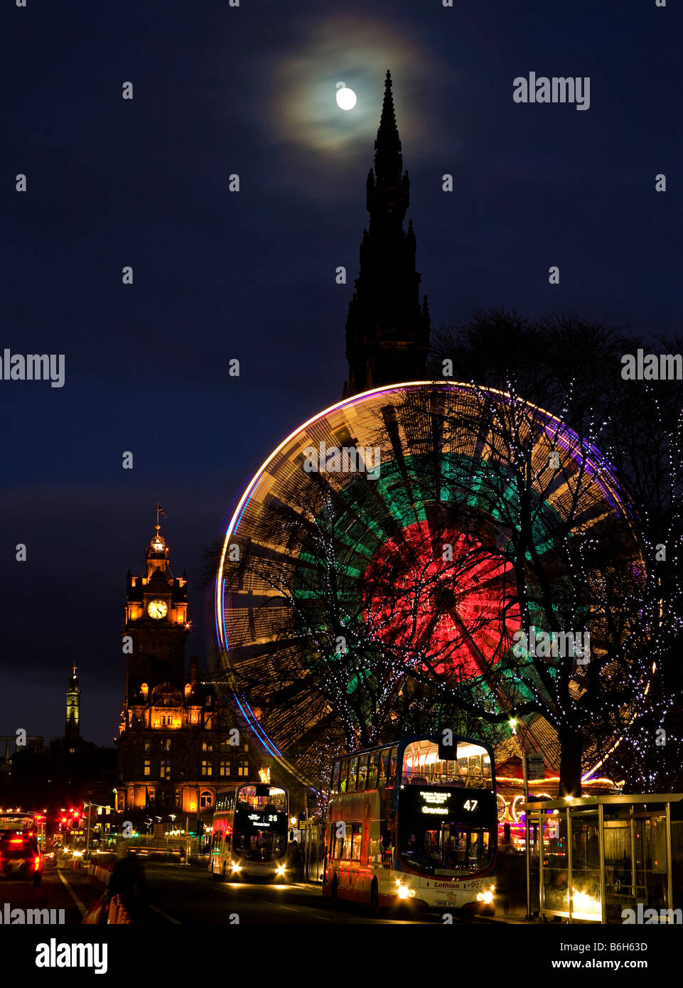 Princes Street, Edinburgh, con il traffico e la ruota panoramica Ferris durante il Natale stagione festiva, Scotland, Regno Unito, Europa Foto Stock