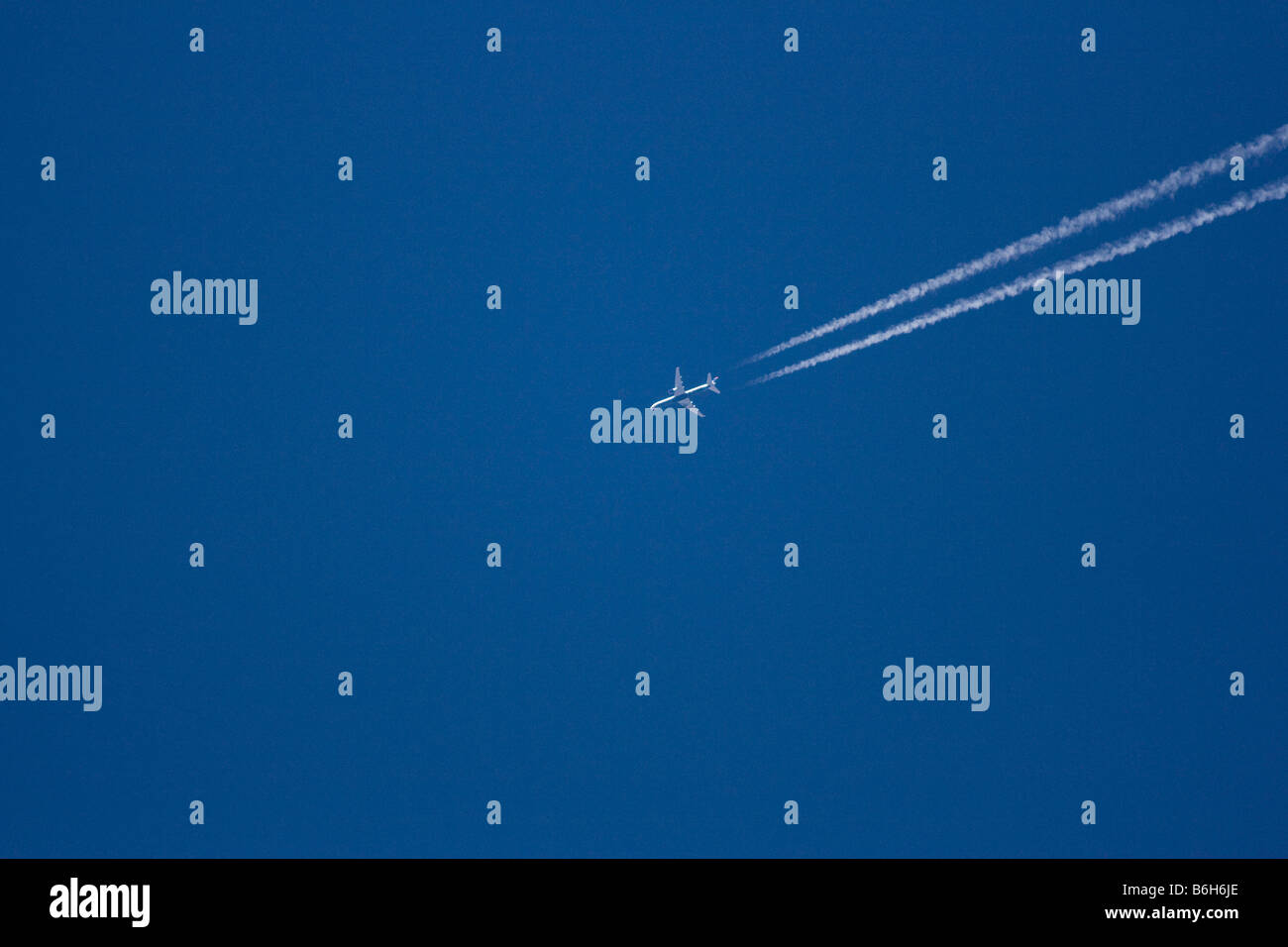 Un aeromobile commerciale in alto nel cielo blu lascia un sentiero di biella e il suo modo di una lontana destinazione Foto Stock