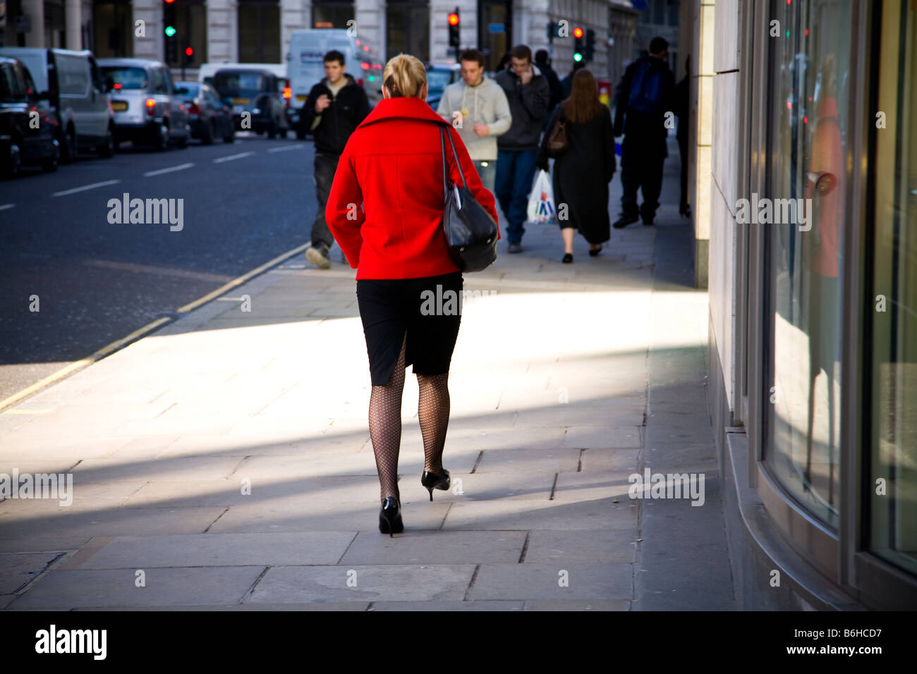 Giovane donna in giacca rossa a piedi nella città di Londra, London, Regno Unito Foto Stock