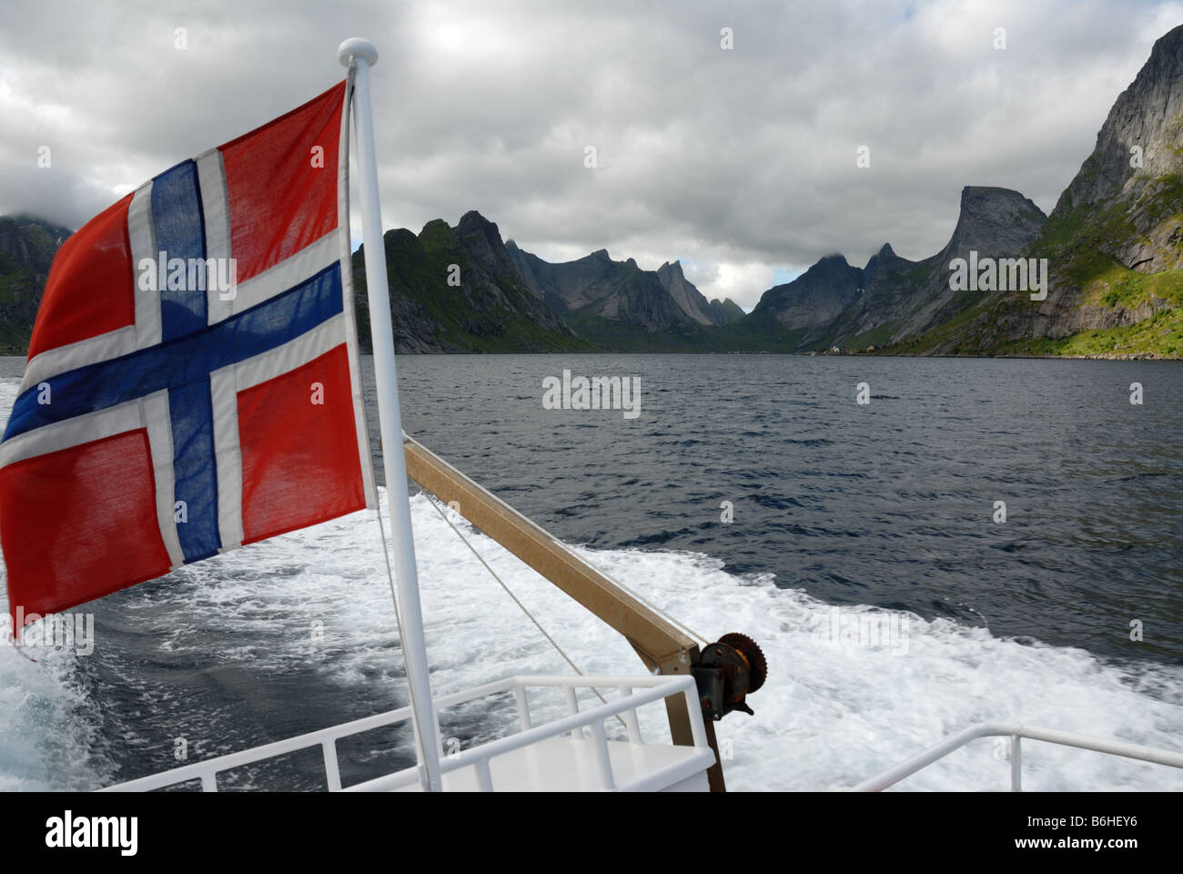 Bandiera norvegese vola da una barca su un fiordo nelle Isole Lofoten Foto Stock