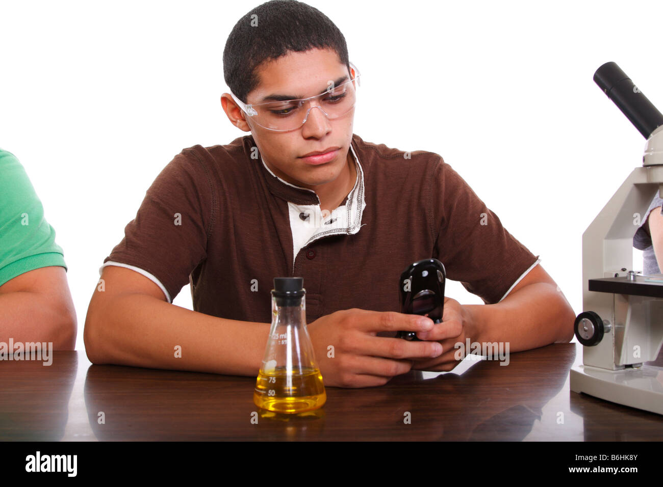 Un adolescente studente in classe utilizzando il suo telefono cellulare Foto Stock